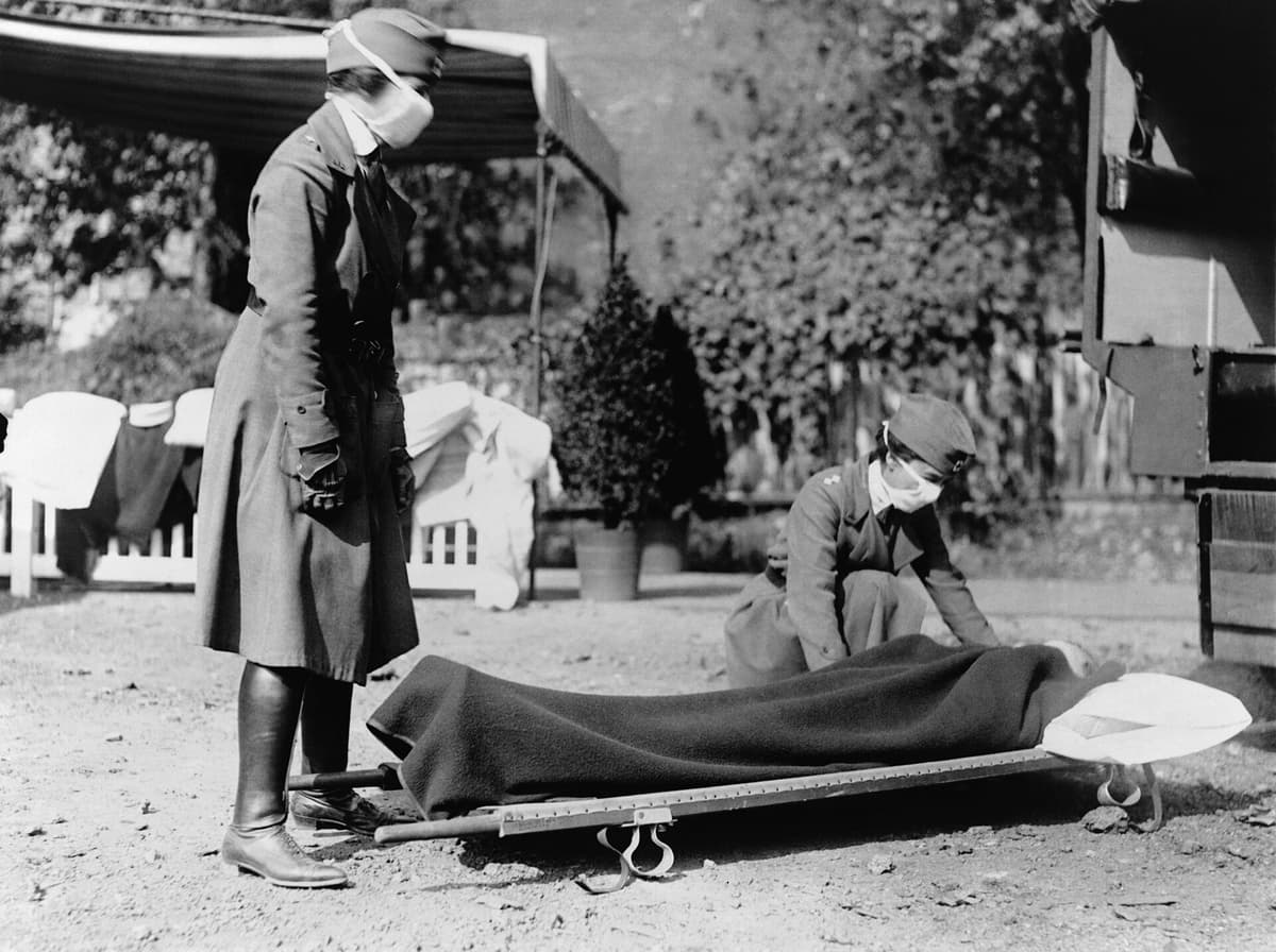 Two Red Cross nurses and a patient on a stretcher at an ambulance station in Washington, DC, during the 1918 influenza pandemic