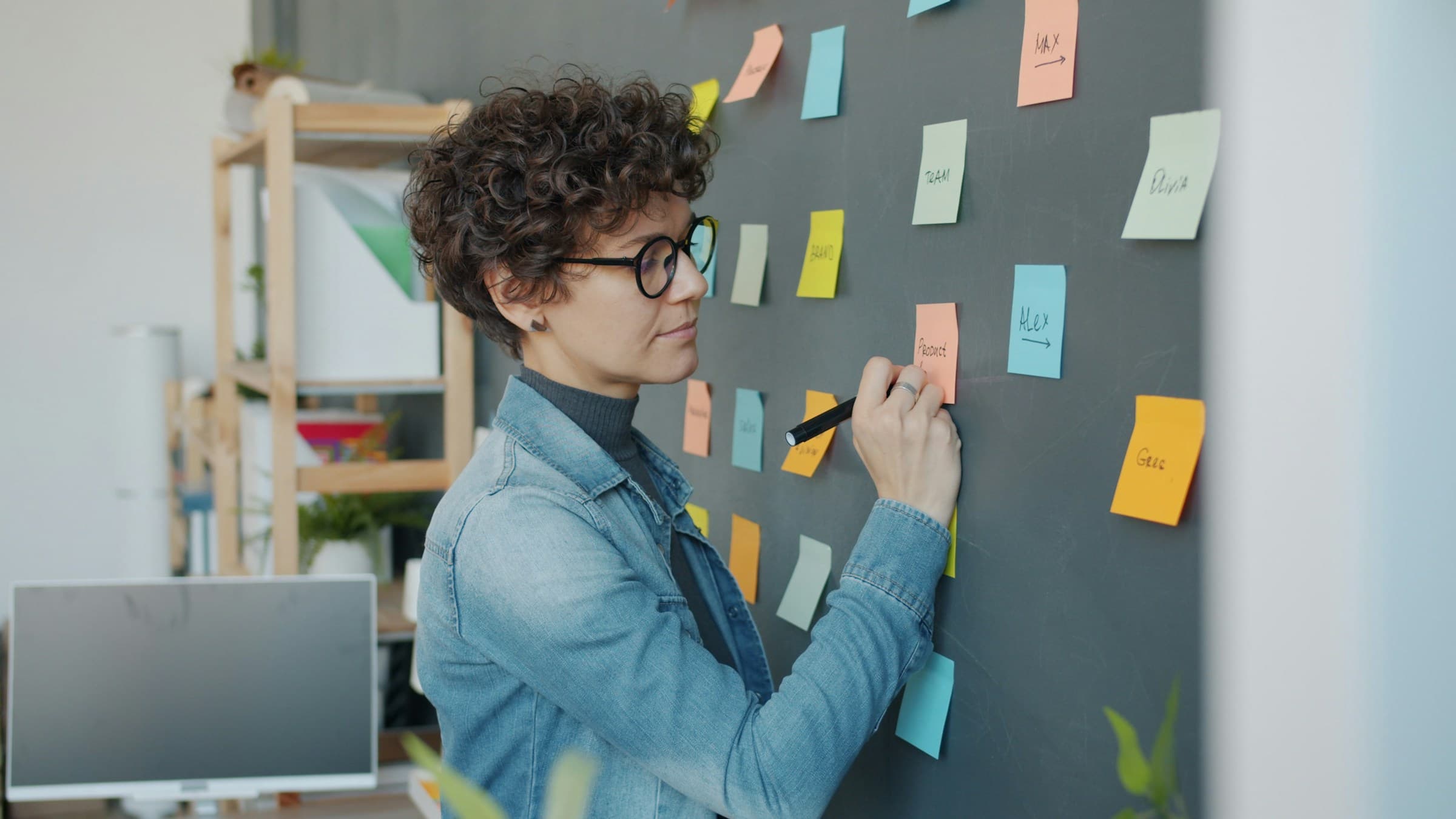 A woman groups colorful sticky notes on a wall.