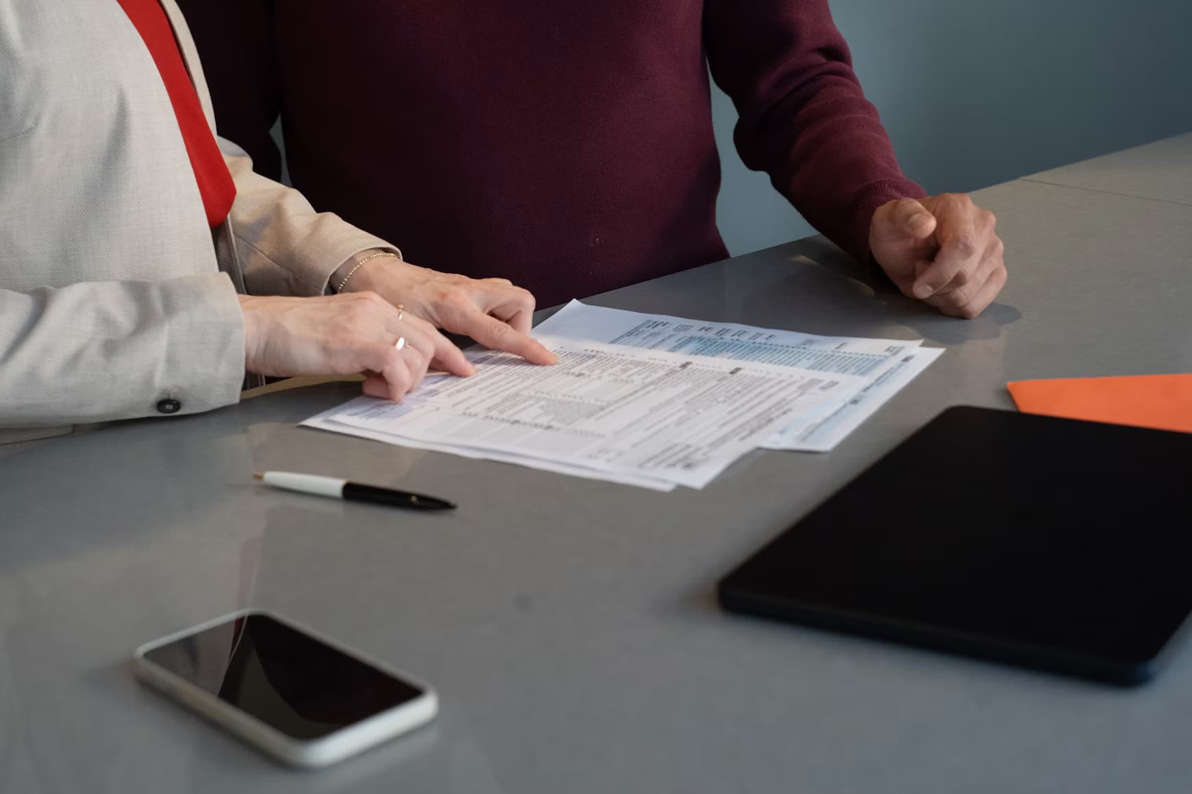 Two people review a printed document together at a conference table.