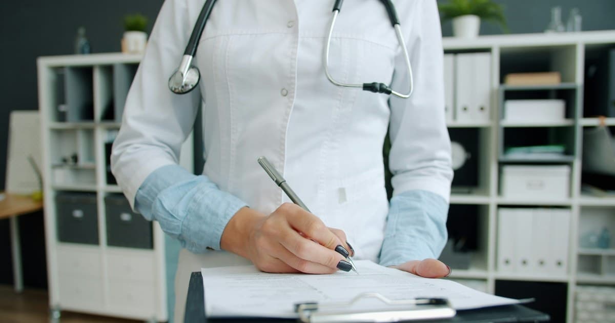 A clinician writes on a clipboard.