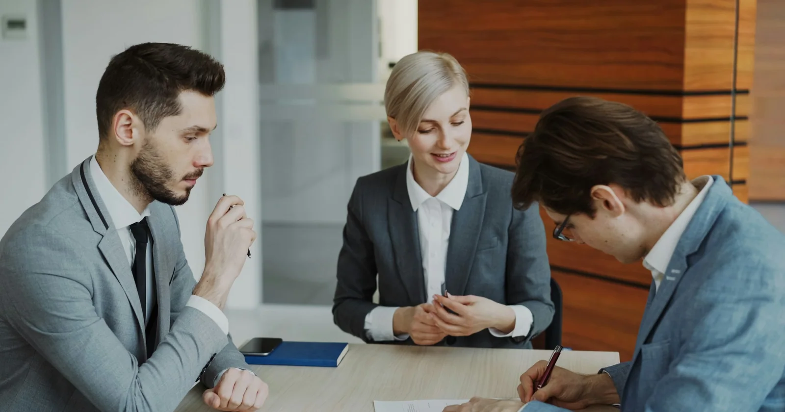 People discuss printed paperwork around a table.