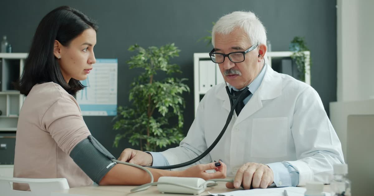 A doctor measures a patient's blood pressure while the patient wears a cuff.
