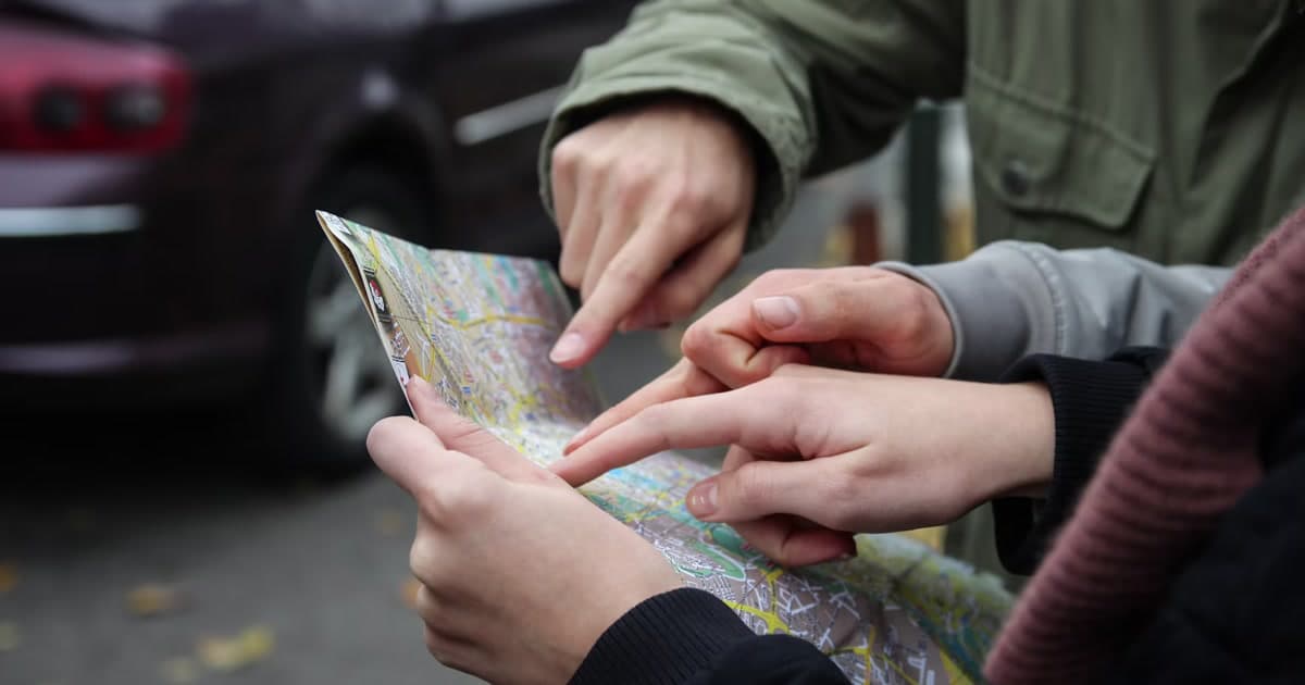 Several hands point to places on a printed city street map.