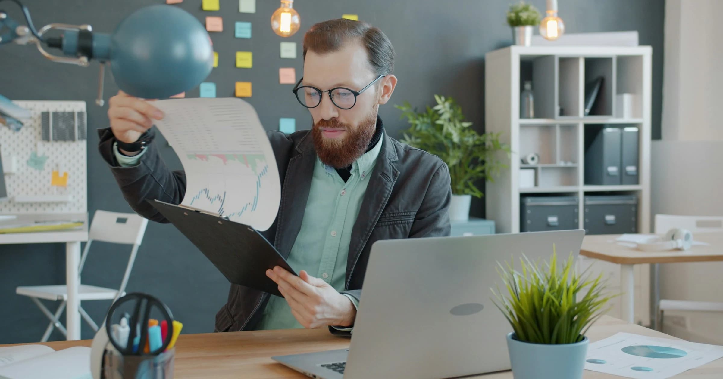 A person reviews a printed chart beside a laptop.
