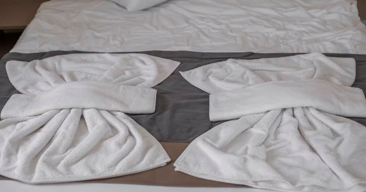 Folded towels arranged on a hotel bed.
