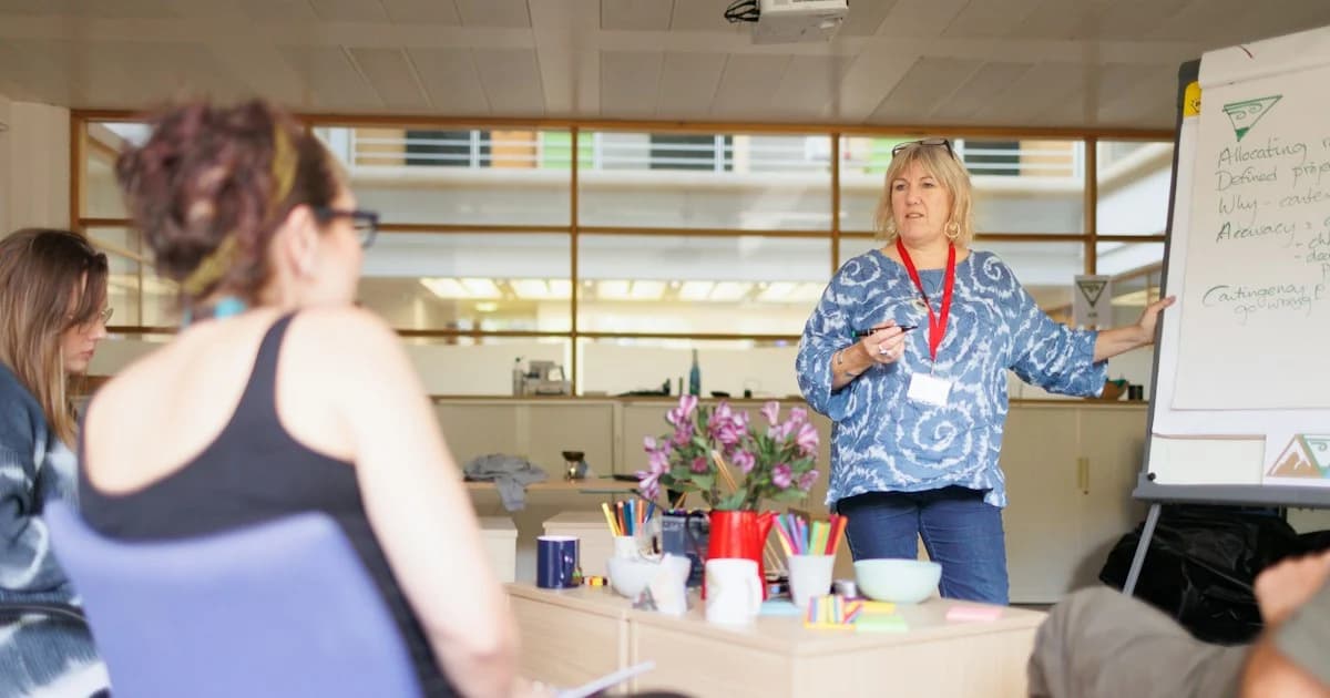 A facilitator leads a workshop and points to a whiteboard.