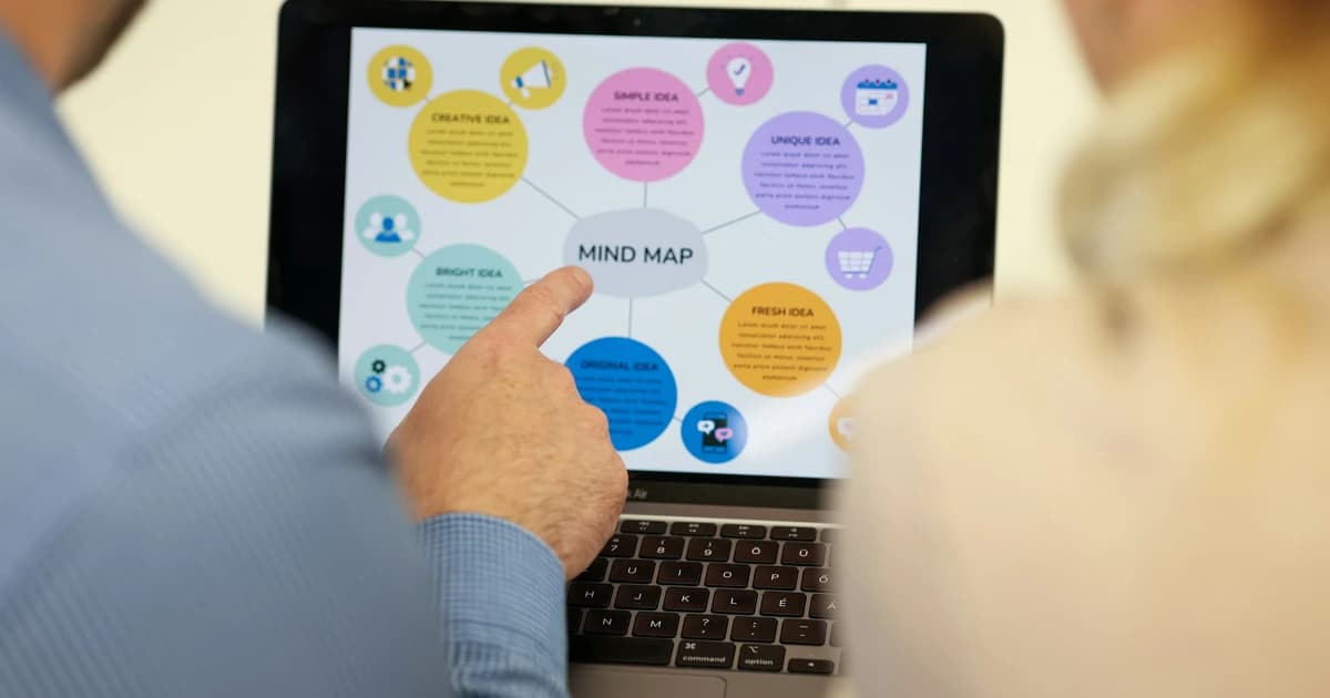 Two people discuss a mind map on a laptop.