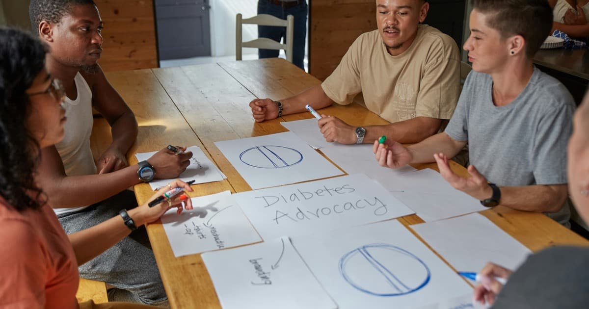 Community members draw and discuss diabetes-advocacy plans at a table.