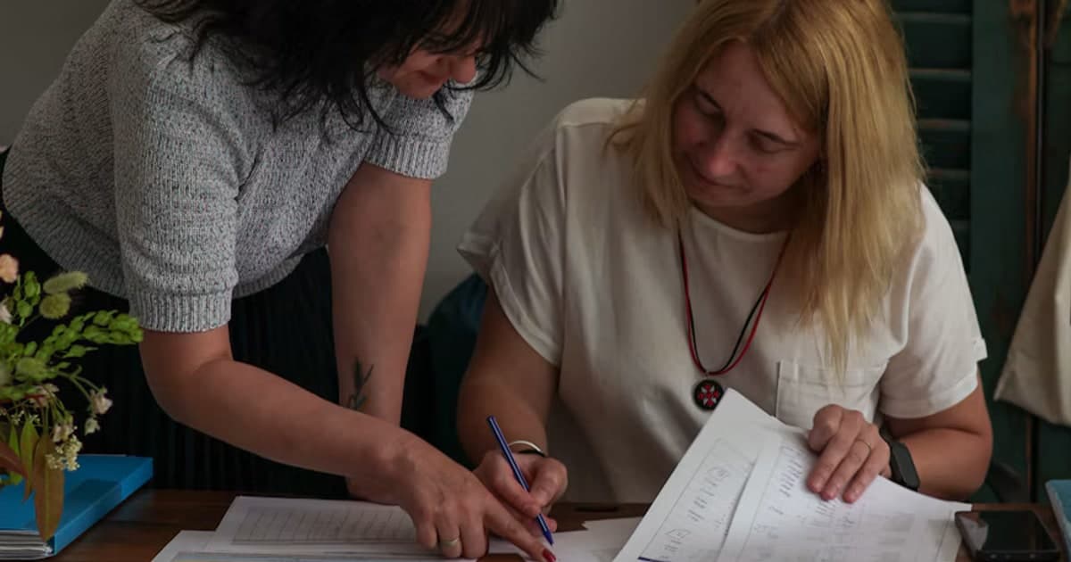 Two women lean over a printed page and review it together.