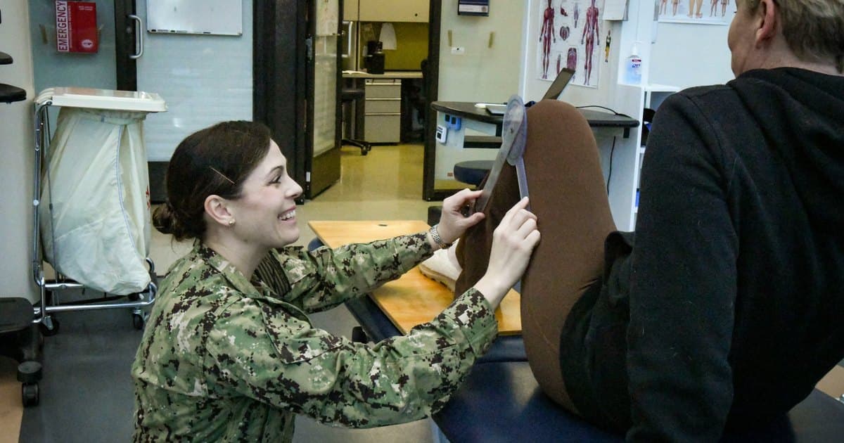A physical therapist measures a patient’s leg during an assessment.