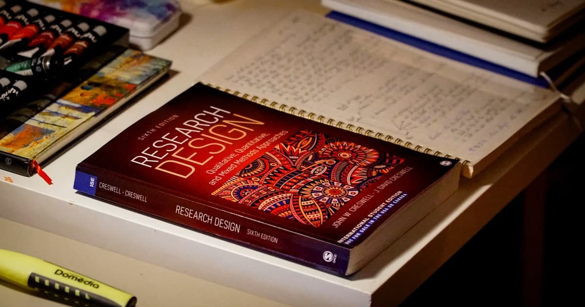 A research design textbook rests beside handwritten notes and art supplies.