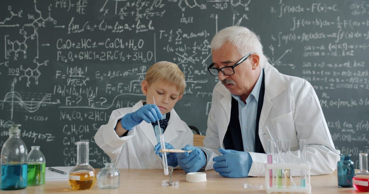 A teacher guides a student through a classroom chemistry experiment.
