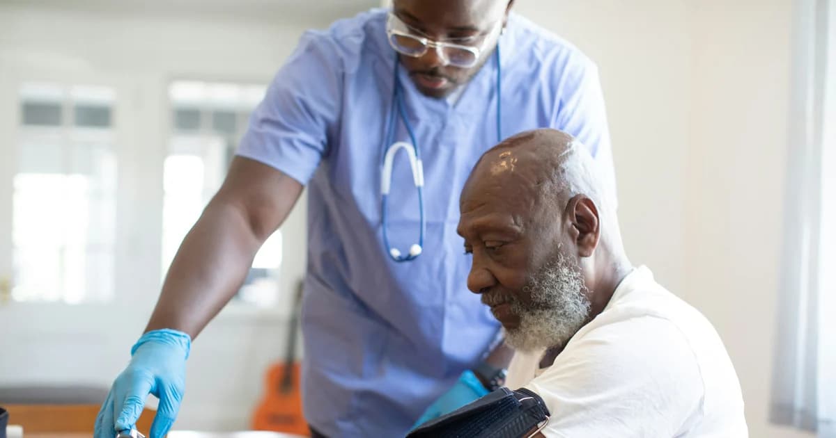 A health worker checks an adult man’s blood pressure.