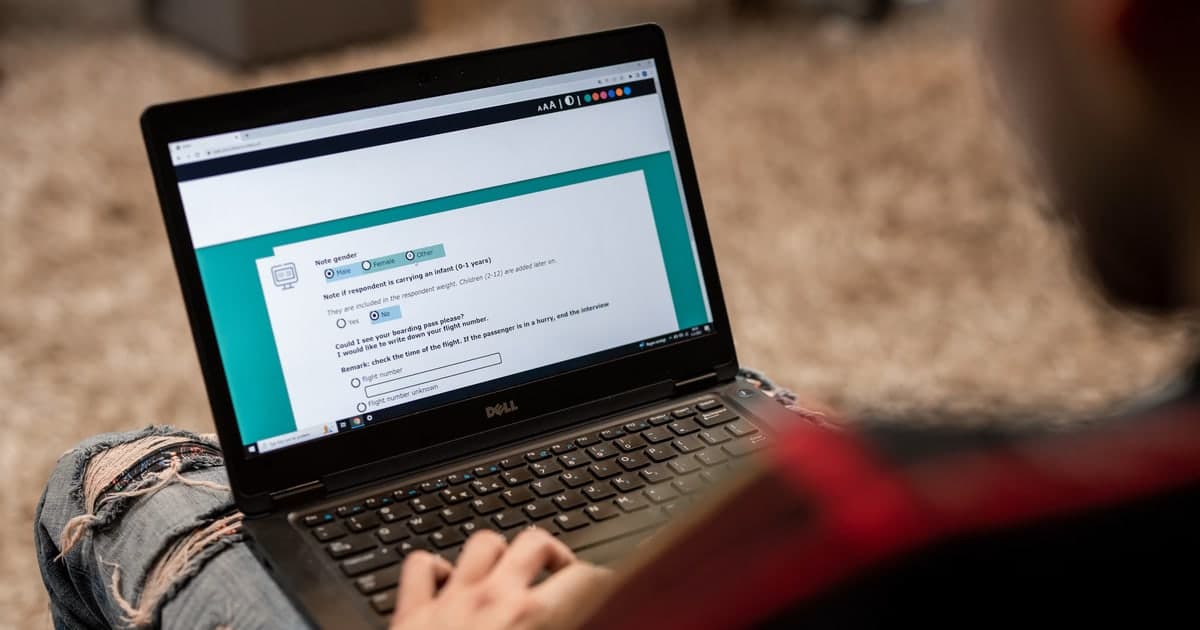 A seated participant completes a questionnaire on a laptop.