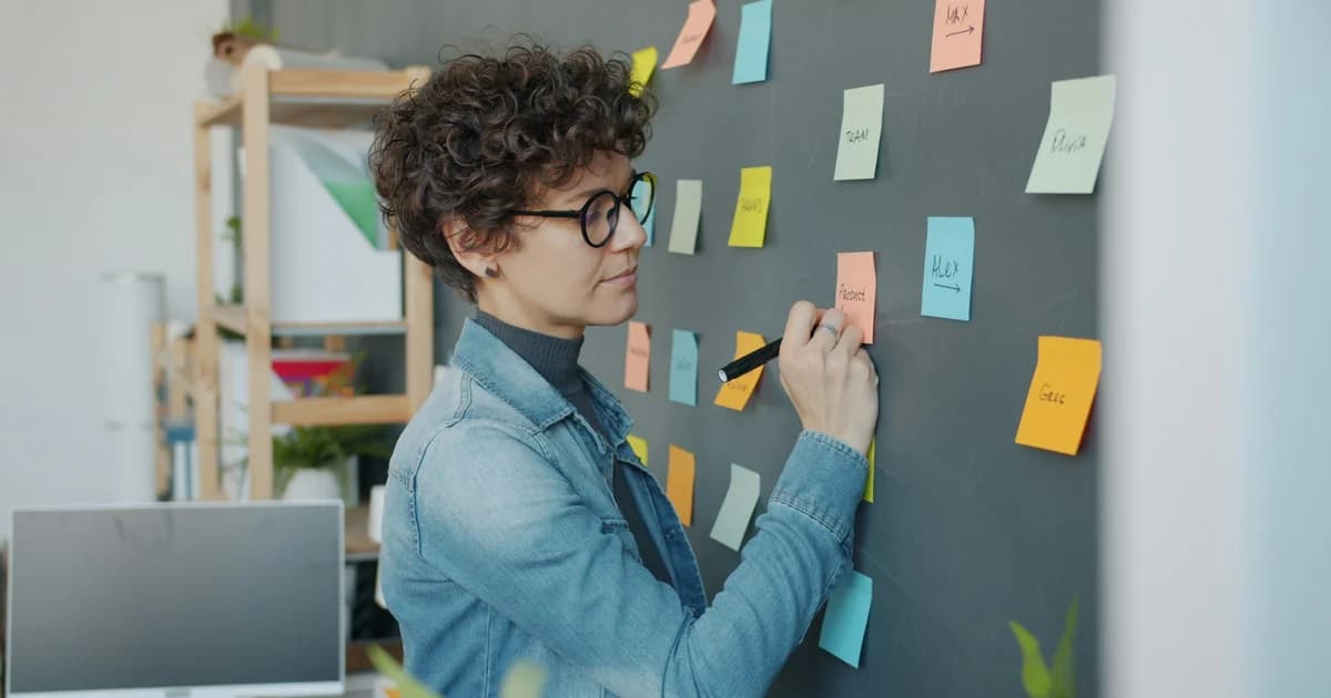 A person places and groups handwritten notes on a wall.